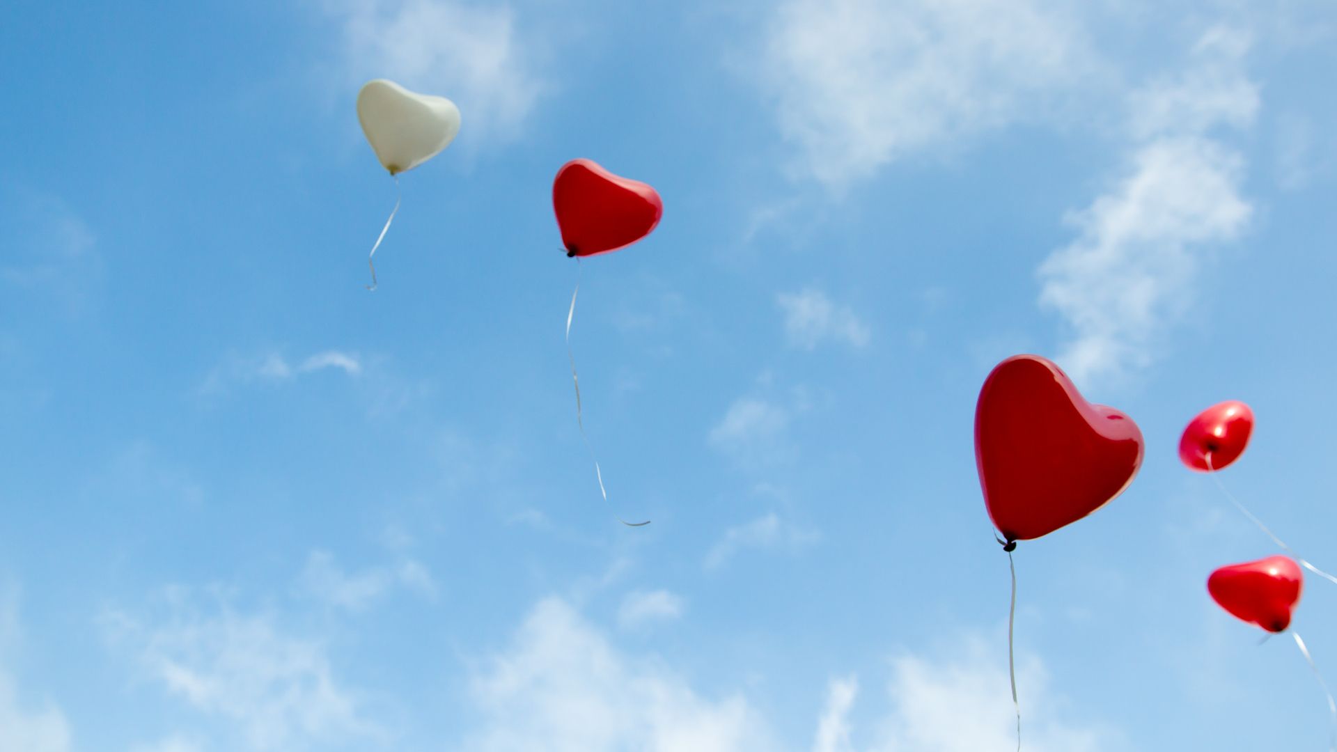 red and white heart balloons floating in the sky