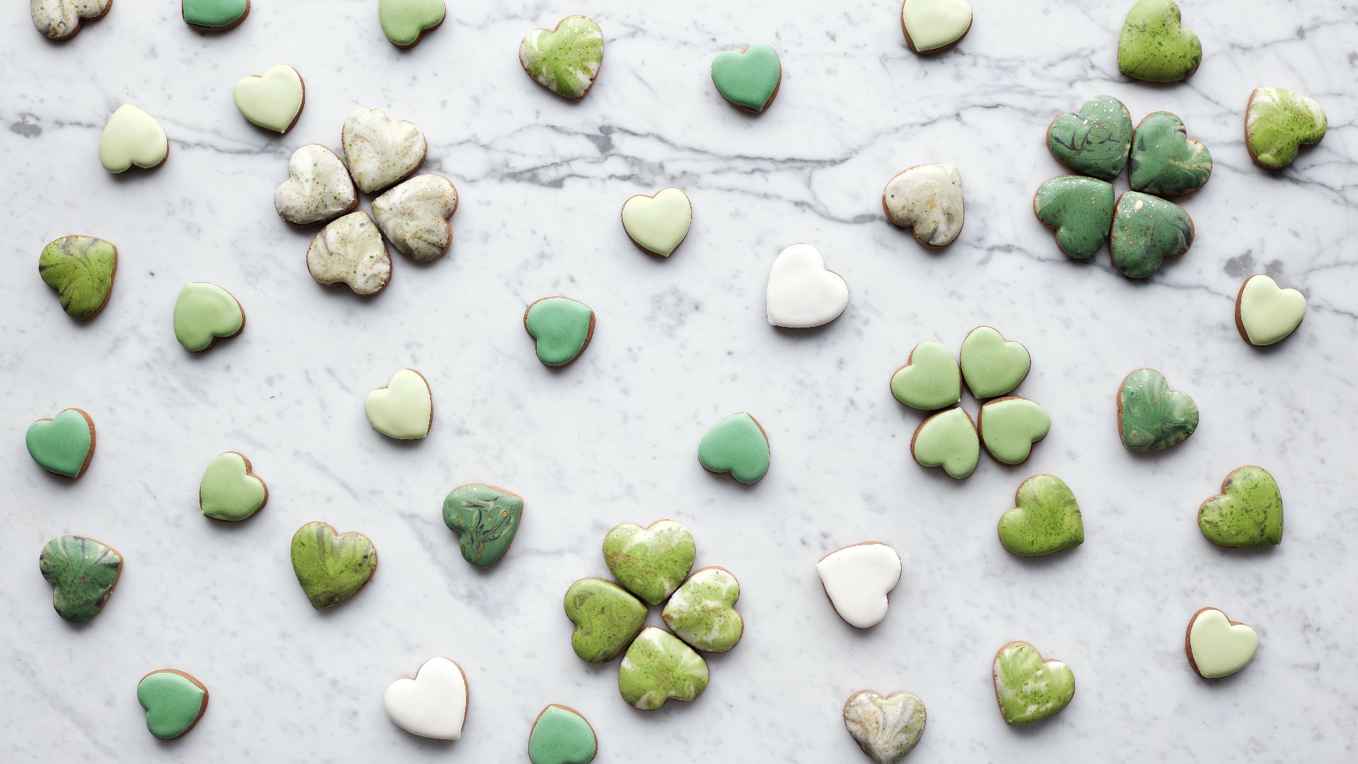 heart shaped cookies with green and white icing on a marble table