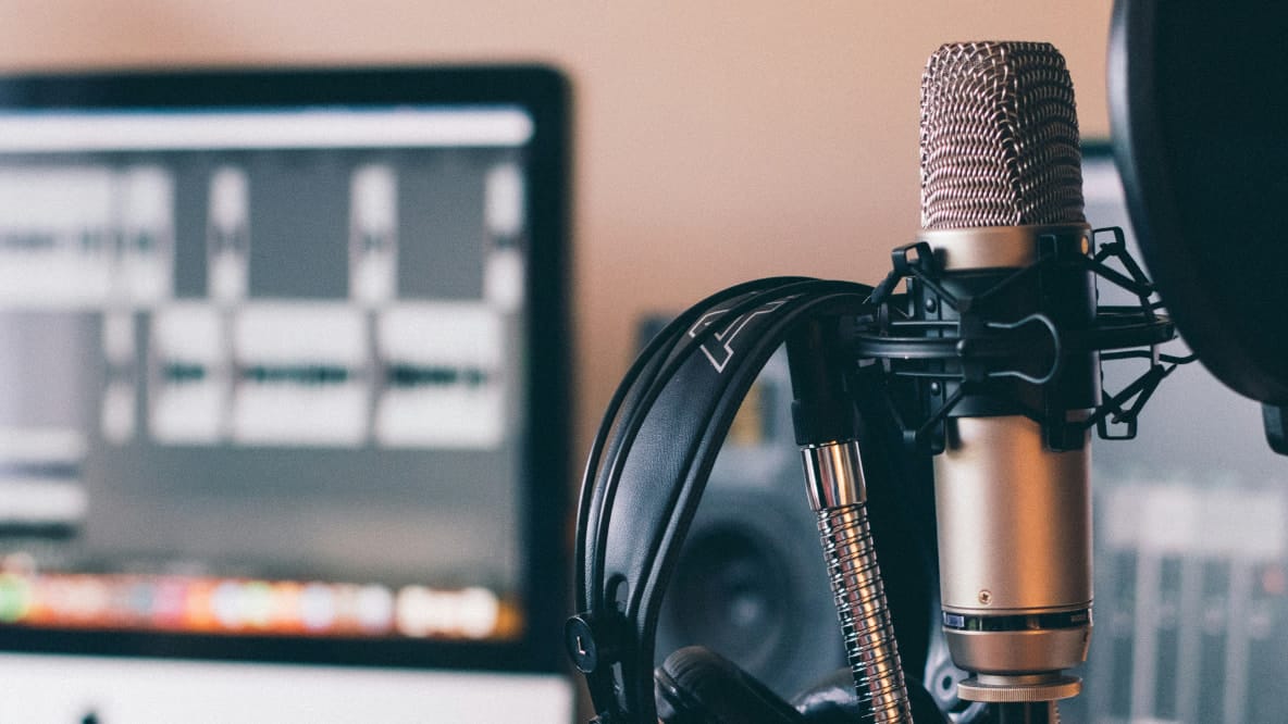 Photograph of a cardioid pattern microphone next to a pop filter and headphones.